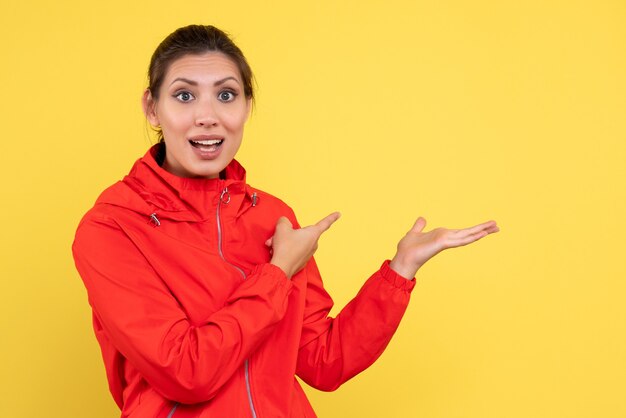 Vista frontal mujer joven en abrigo rojo sobre fondo amarillo