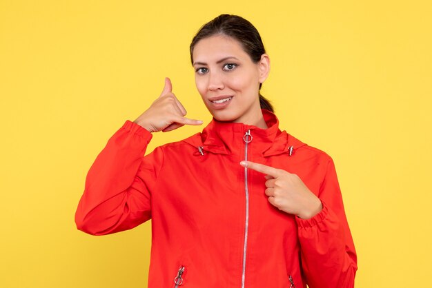 Vista frontal mujer joven en abrigo rojo sobre fondo amarillo