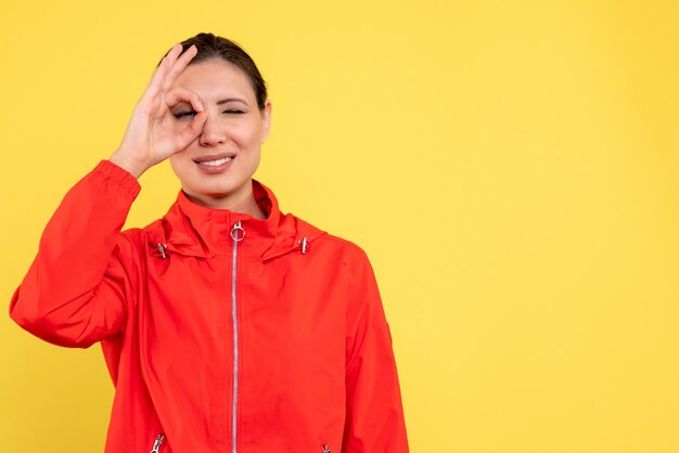 Vista frontal mujer joven en abrigo rojo sobre fondo amarillo