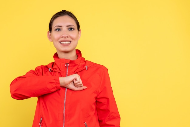 Vista frontal mujer joven en abrigo rojo sobre fondo amarillo