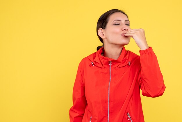 Vista frontal mujer joven en abrigo rojo sobre fondo amarillo