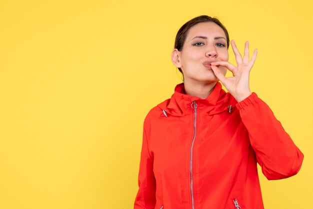 Vista frontal mujer joven en abrigo rojo sobre fondo amarillo