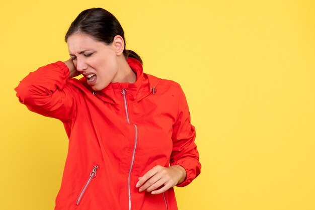 Vista frontal mujer joven en abrigo rojo sobre fondo amarillo