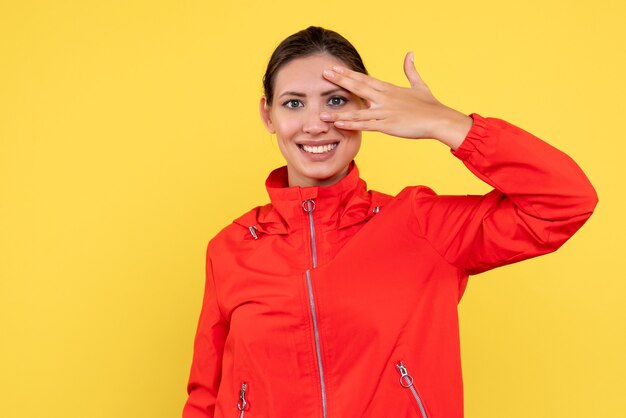 Vista frontal mujer joven en abrigo rojo sobre fondo amarillo