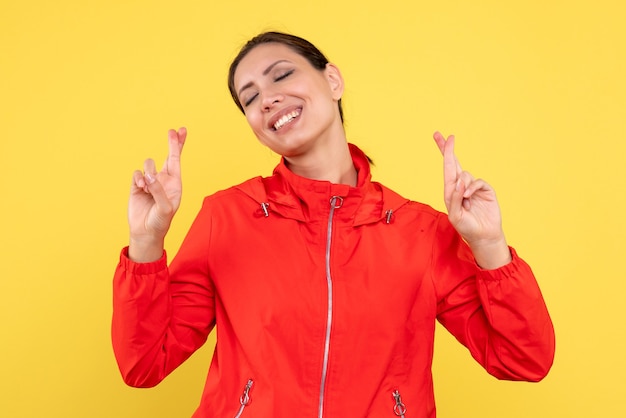 Vista frontal mujer joven en abrigo rojo sobre fondo amarillo