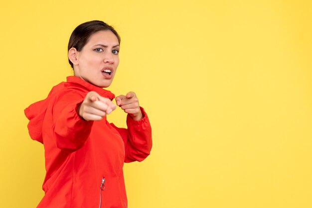 Vista frontal mujer joven en abrigo rojo sobre fondo amarillo