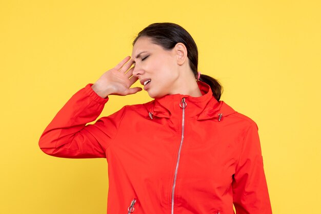 Vista frontal mujer joven en abrigo rojo sobre fondo amarillo