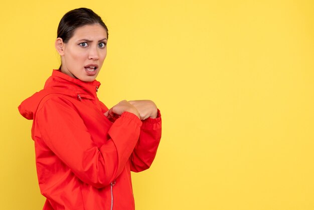 Vista frontal mujer joven en abrigo rojo sobre fondo amarillo