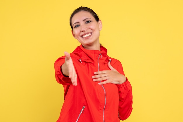 Vista frontal mujer joven en abrigo rojo sobre fondo amarillo