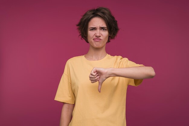 Vista frontal, de, un, mujer joven, actuación, el, pulgar abajo, señal