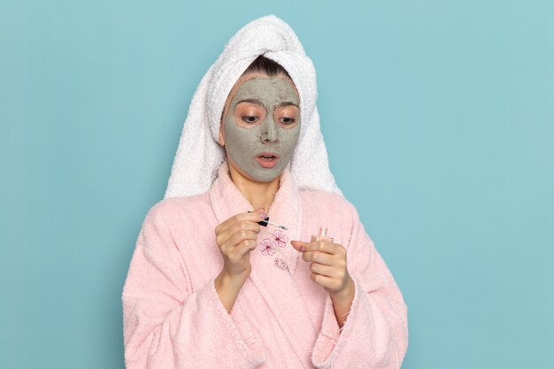 Vista frontal mujer joven en bata de baño rosa después de la ducha en la pared azul claro ducha de autocuidado de agua limpia de belleza