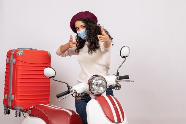Vista frontal mujer joven con bicicleta en máscara sobre fondo blanco virus velocidad del vehículo covid- motocicleta color de la carretera