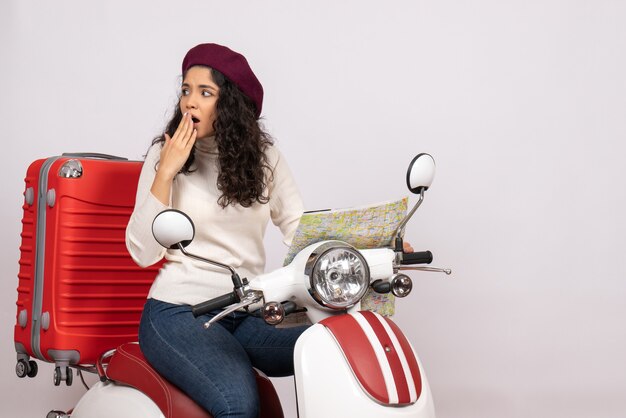 Vista frontal mujer joven en bicicleta sosteniendo mapa sobre fondo blanco ciudad color carretera vacaciones vehículo velocidad de paseo