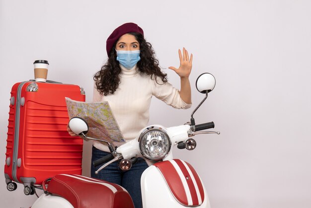 Vista frontal mujer joven con bicicleta sosteniendo mapa sobre un fondo blanco color covid- pandemia motocicleta paseo ciudad virus vehículo de velocidad