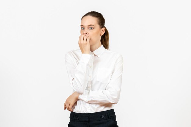 Vista frontal mujer joven en blusa blanca con cara nerviosa sobre fondo blanco trabajo de oficina emoción femenina modelo de sentimiento