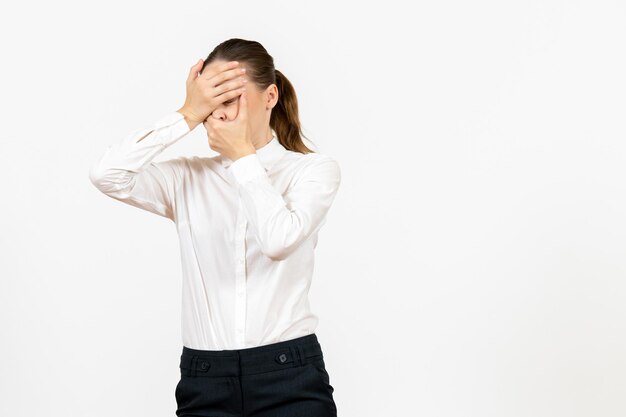 Vista frontal mujer joven en blusa blanca con cara nerviosa sobre fondo blanco trabajo de oficina modelo de sentimientos de emociones femeninas