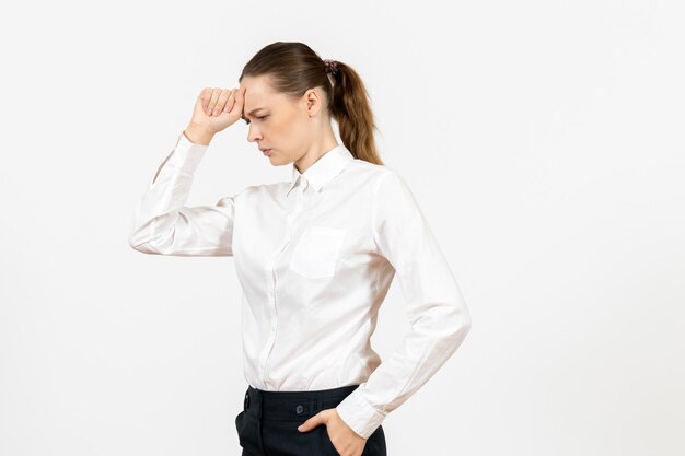 Vista frontal mujer joven en blusa blanca con cara de pensamiento sobre fondo blanco oficina emoción femenina sentimiento modelo trabajo