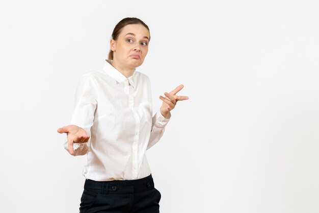 Vista frontal mujer joven en blusa blanca con expresión confusa sobre fondo blanco sentimiento modelo oficina de trabajo emoción femenina