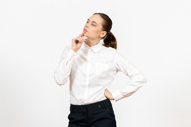 Vista frontal mujer joven en blusa blanca con expresión de pensamiento sobre fondo blanco trabajo de oficina emoción femenina modelo de sentimiento