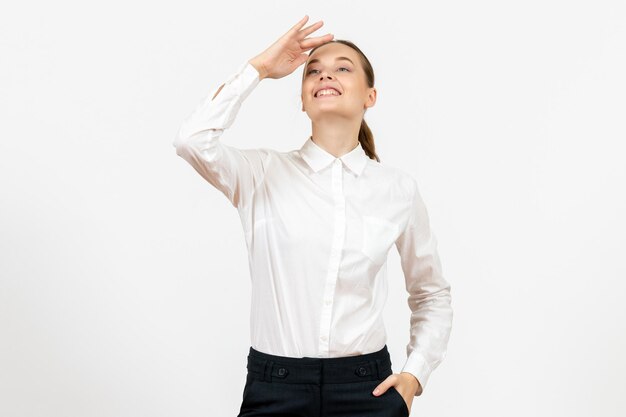 Vista frontal mujer joven en blusa blanca mirando a distancia sobre fondo blanco oficina emoción femenina sentimiento modelo trabajo