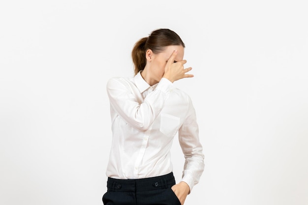 Vista frontal mujer joven en blusa blanca que cubre su rostro sobre fondo blanco oficina de trabajo modelo de sentimiento de emoción femenina