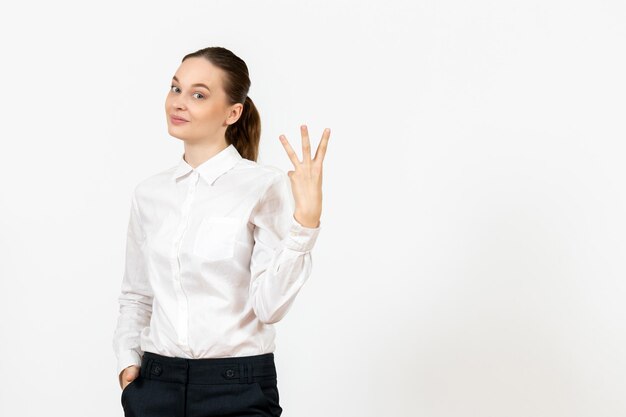 Vista frontal mujer joven en blusa blanca con rostro encantado sobre fondo blanco oficina de trabajo sentimiento femenino modelo emoción