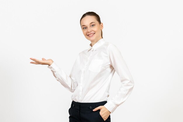 Vista frontal mujer joven en blusa blanca con rostro sonriente sobre fondo blanco oficina de trabajo sentimiento femenino modelo emoción