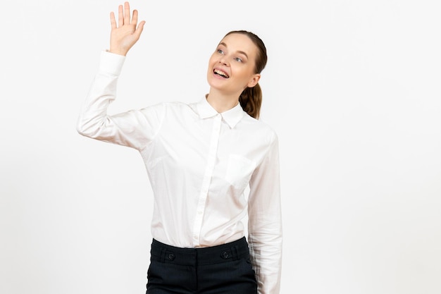Vista frontal mujer joven en blusa blanca saludando a alguien sobre fondo blanco trabajo de oficina emoción femenina modelo de sentimiento