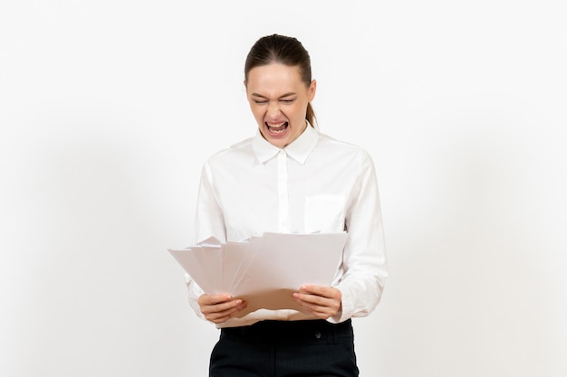 Vista frontal mujer joven en blusa blanca sosteniendo archivos sobre fondo blanco emociones femeninas sentimiento trabajo de oficina