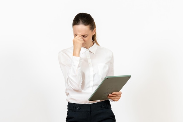 Vista frontal mujer joven en blusa blanca sosteniendo enorme calculadora sobre fondo blanco oficina emociones femeninas sentimiento trabajo