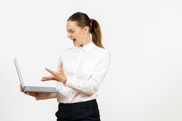 Vista frontal mujer joven en blusa blanca usando laptop y gritando sobre fondo blanco oficina de trabajo sentimiento femenino modelo emoción