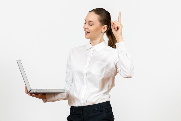 Vista frontal mujer joven en blusa blanca usando laptop sobre fondo blanco modelo oficina de trabajo sentimiento emoción femenina