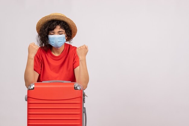 Vista frontal mujer joven con bolsa en máscara sobre fondo blanco color covid- viaje pandémico virus turístico solar