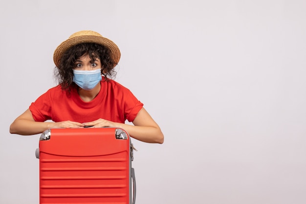 Vista frontal mujer joven con bolsa en máscara sobre fondo blanco color covid- virus del sol pandémico viaje vacaciones turísticas