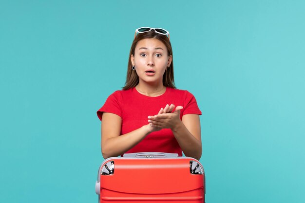 Vista frontal mujer joven con bolsa roja aplaudiendo en espacio azul