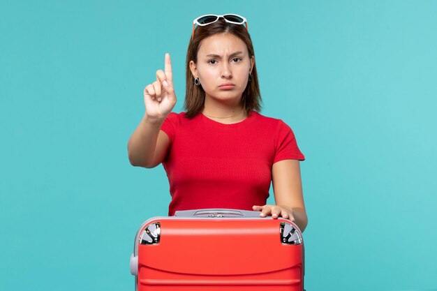 Vista frontal mujer joven con bolsa roja en el espacio azul