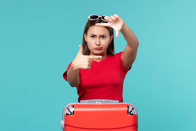 Vista frontal mujer joven con bolsa roja y posando en espacio azul