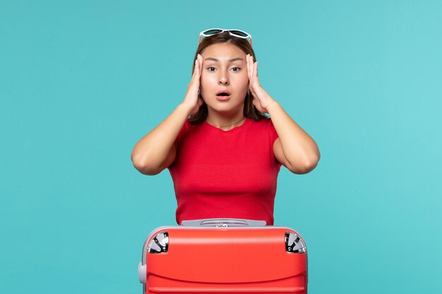 Vista frontal mujer joven con bolsa roja que tiene dolor de cabeza en el espacio azul