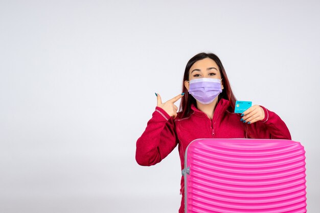 Vista frontal mujer joven con bolsa rosa en máscara en la pared blanca virus mujer vacaciones covid pandemia de color