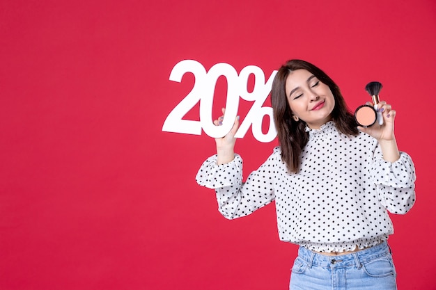 Foto gratuita vista frontal mujer joven con borla en polvo para maquillaje y escritura en pared roja