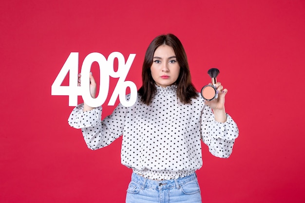 Foto gratuita vista frontal mujer joven con borla en polvo para maquillaje y escritura en pared roja