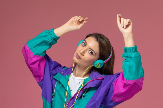 Vista frontal mujer joven en camisa blanca abrigo colorido escuchando música y bailando