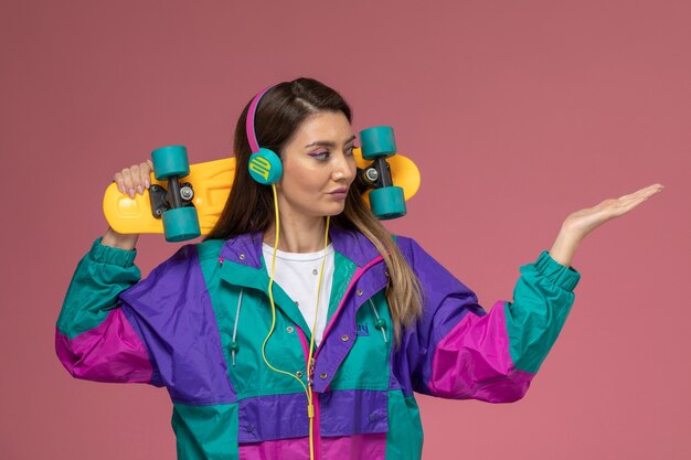 Vista frontal mujer joven en camisa blanca abrigo colorido con patineta