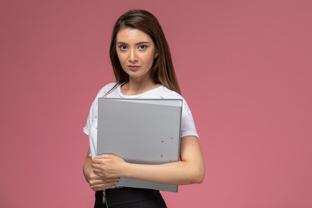 Vista frontal mujer joven en camisa blanca con documento gris