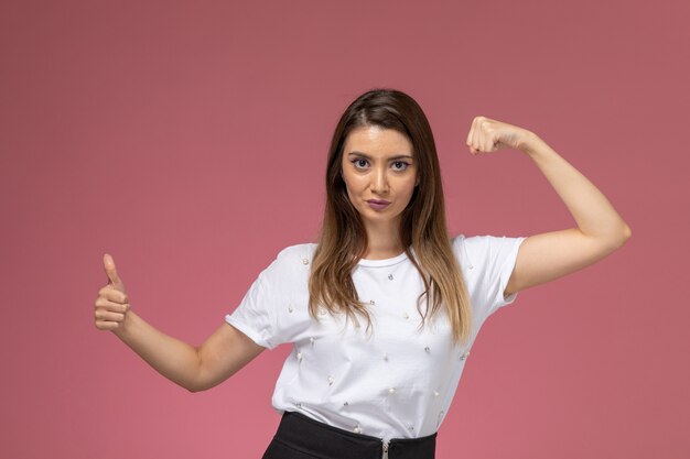 Vista frontal mujer joven en camisa blanca flexionando y mostrando como signo, modelo de mujer de color posando mujer