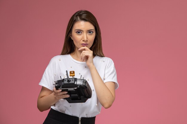 Vista frontal mujer joven en camisa blanca sosteniendo el pensamiento de control remoto