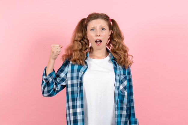 Vista frontal mujer joven en camisa a cuadros azul con expresión confusa sobre fondo rosa mujer emociones modelo moda niñas color