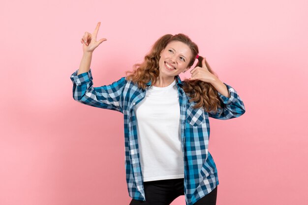 Vista frontal mujer joven en camisa a cuadros azul con expresión feliz en el fondo rosa mujer emociones modelo moda niñas color