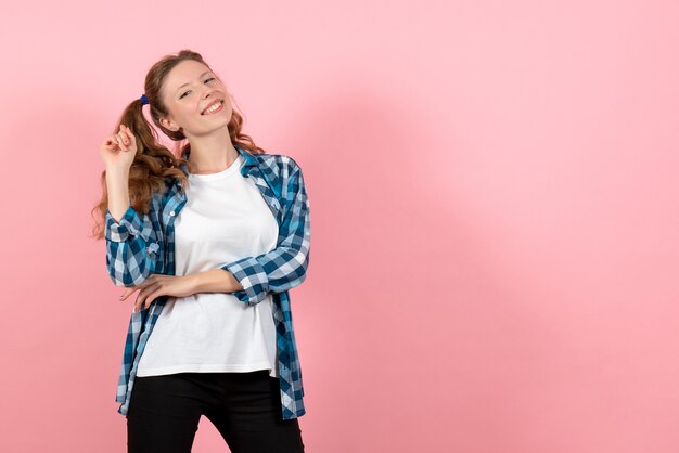 Vista frontal mujer joven en camisa a cuadros azul posando en el modelo de emoción de color de fondo rosa mujer niño juventud color