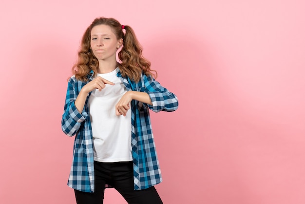 Vista frontal mujer joven en camisa a cuadros azul posando en rosa escritorio niño juventud emoción modelo mujer color